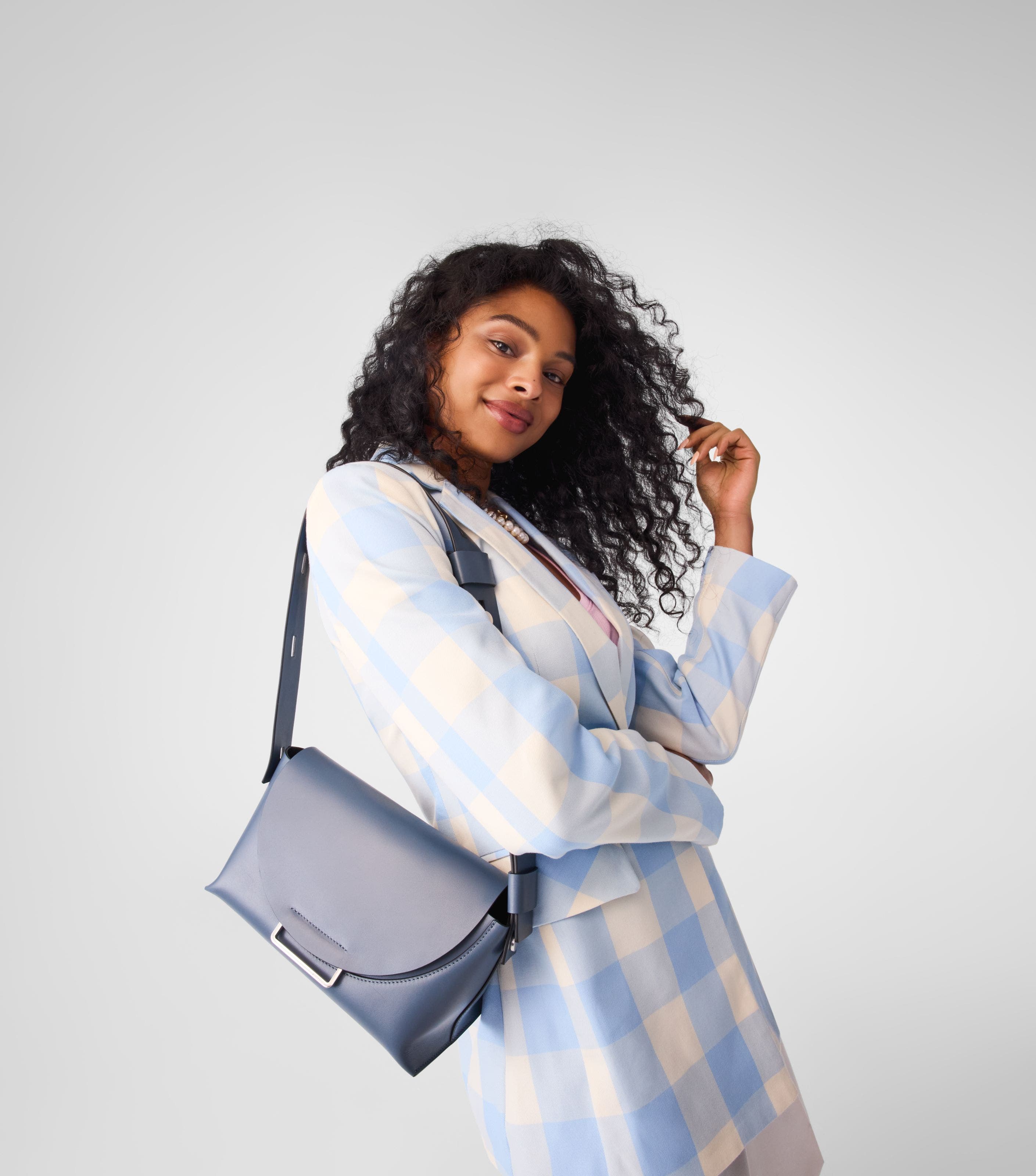 A woman carrying a grey-blue handbag. 