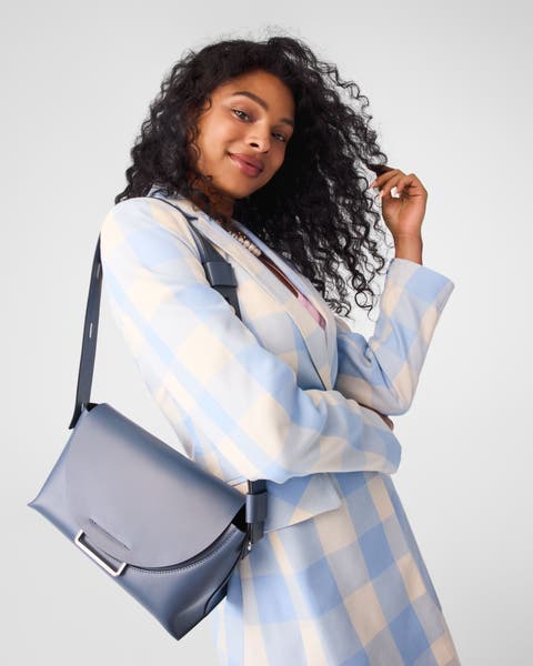 A woman carrying a grey-blue handbag.