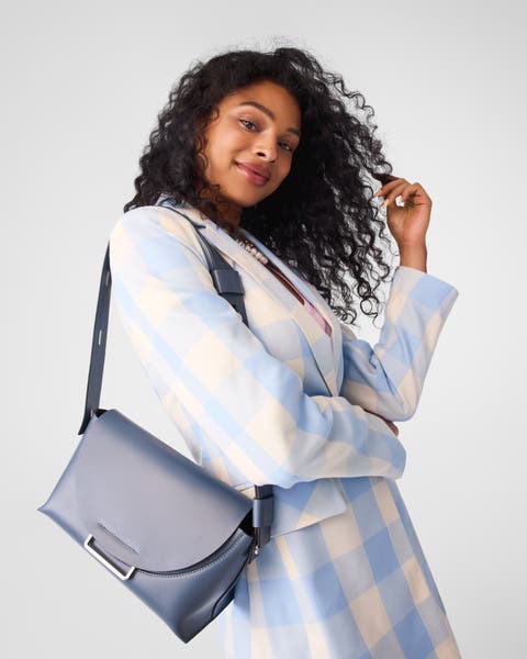 A woman carrying a grey-blue handbag.