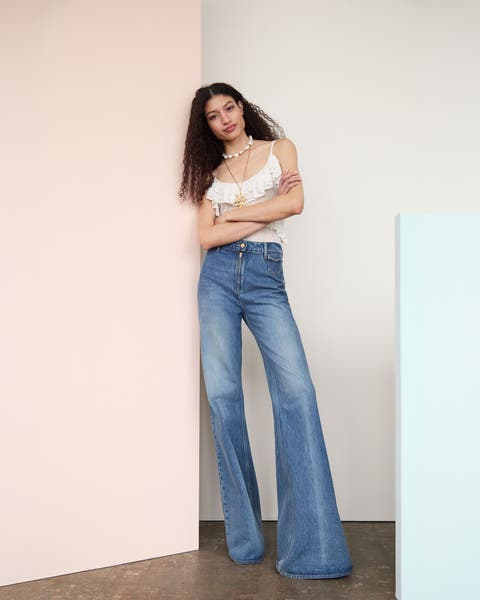 Woman wearing a tank, jeans and layered necklaces.
