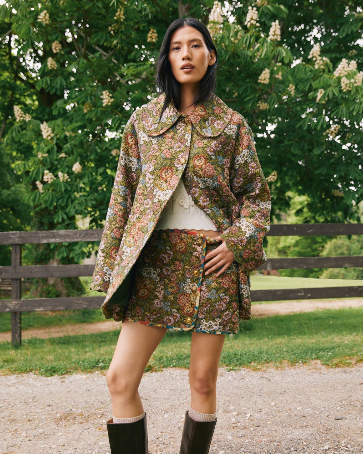 A woman wearing a floral jacket and skirt.