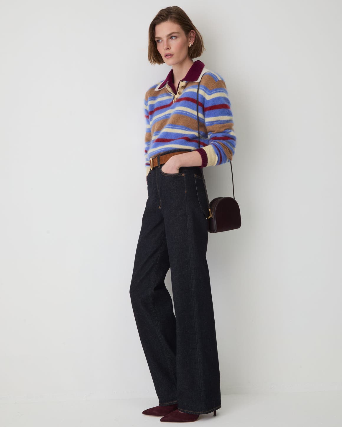 A woman wearing a polo sweater and dark wash jeans.