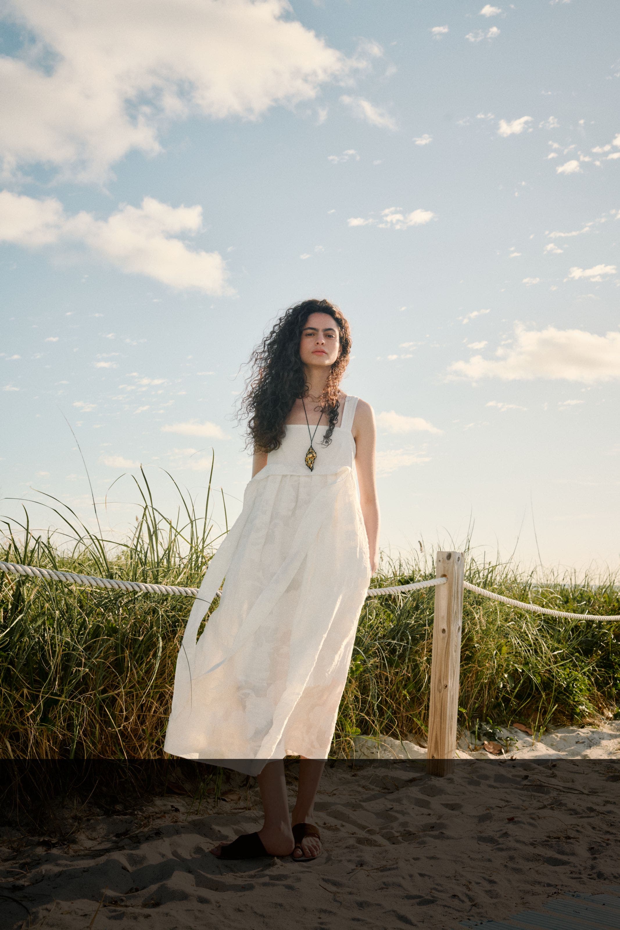 Woman wearing a white dress and necklace.