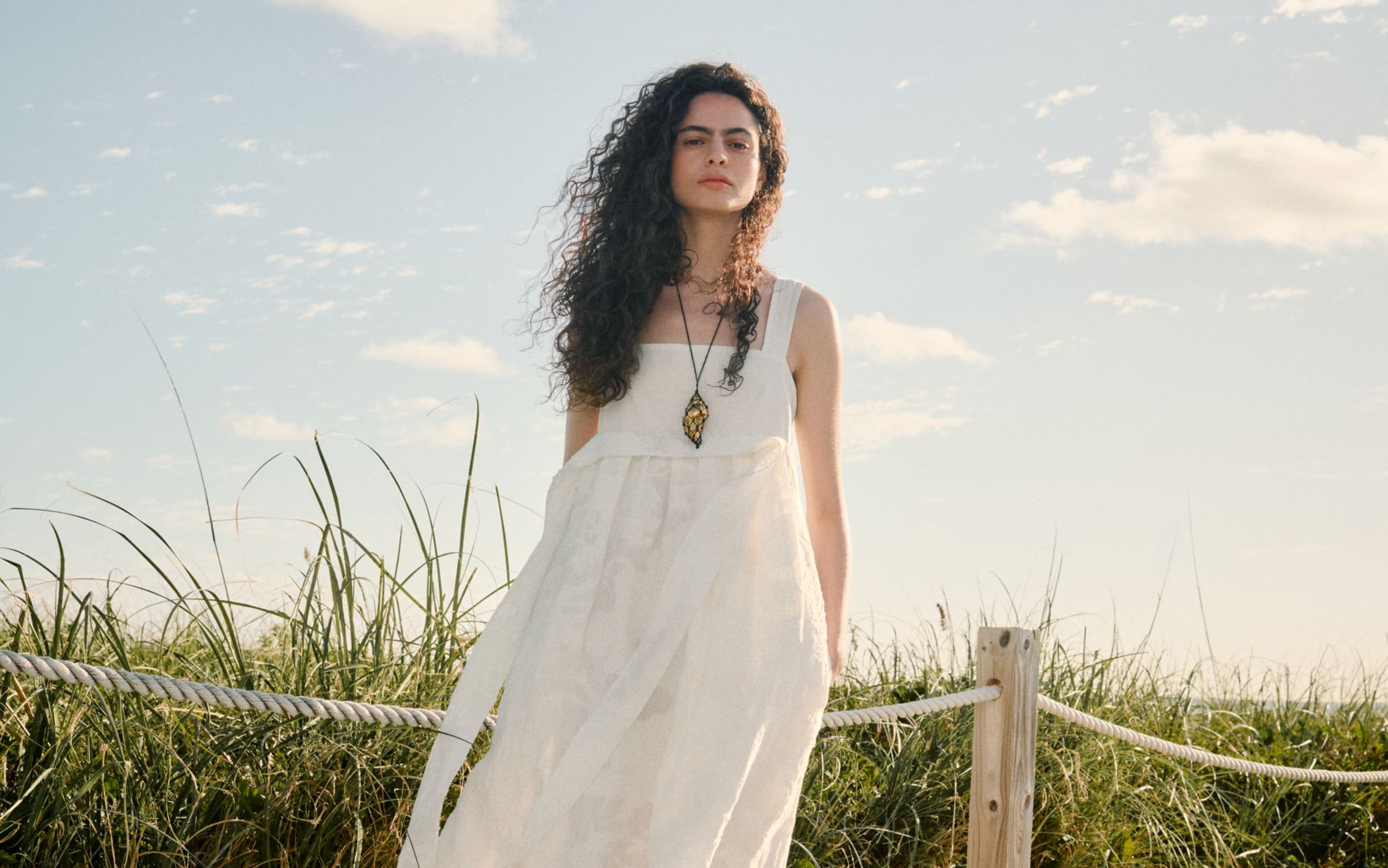 Woman wearing a white dress and necklace.