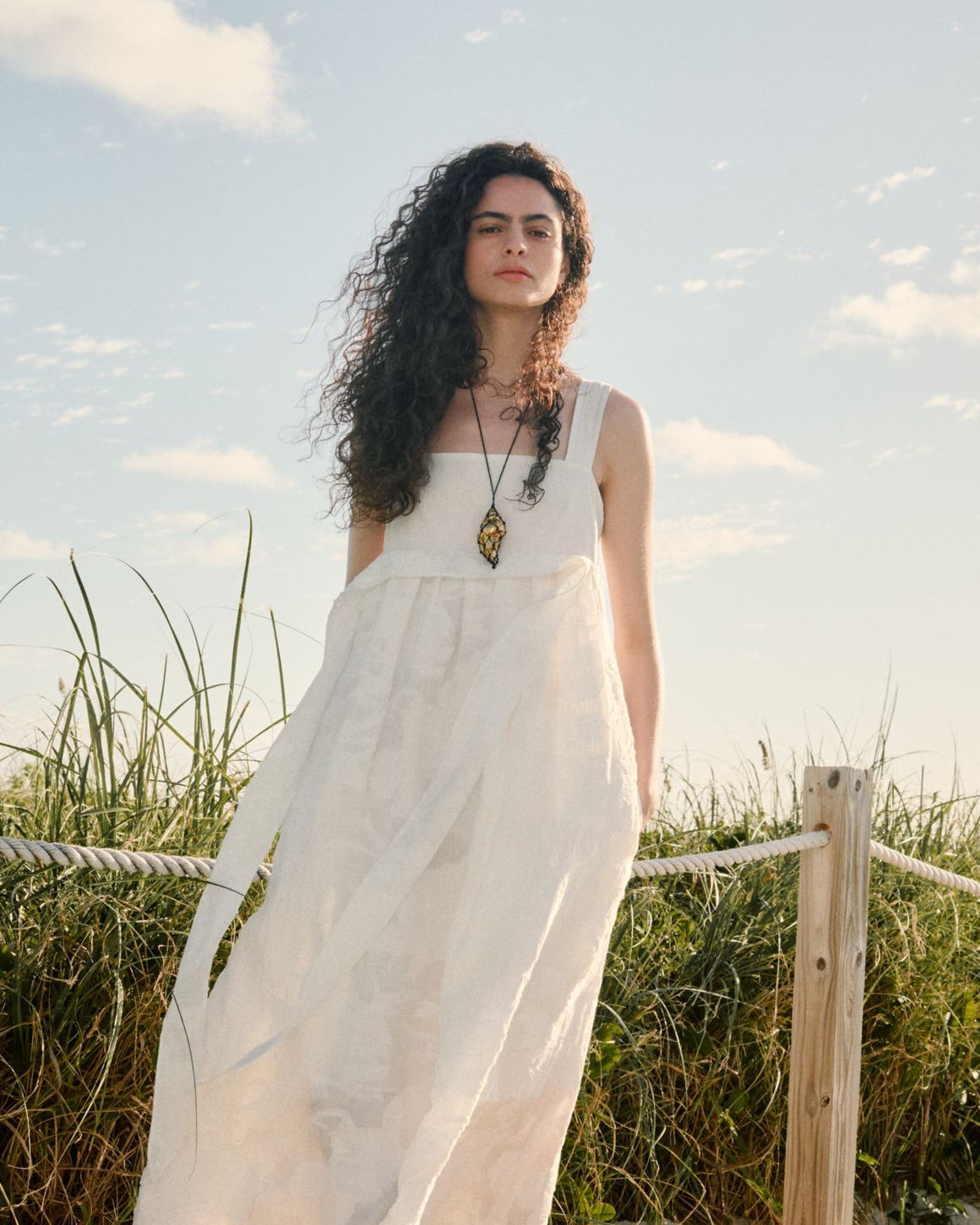 Woman wearing a white dress and necklace.