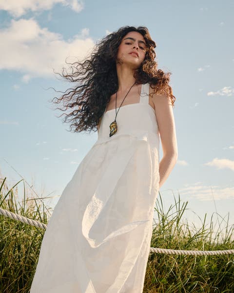 Woman wearing a white dress and necklace.