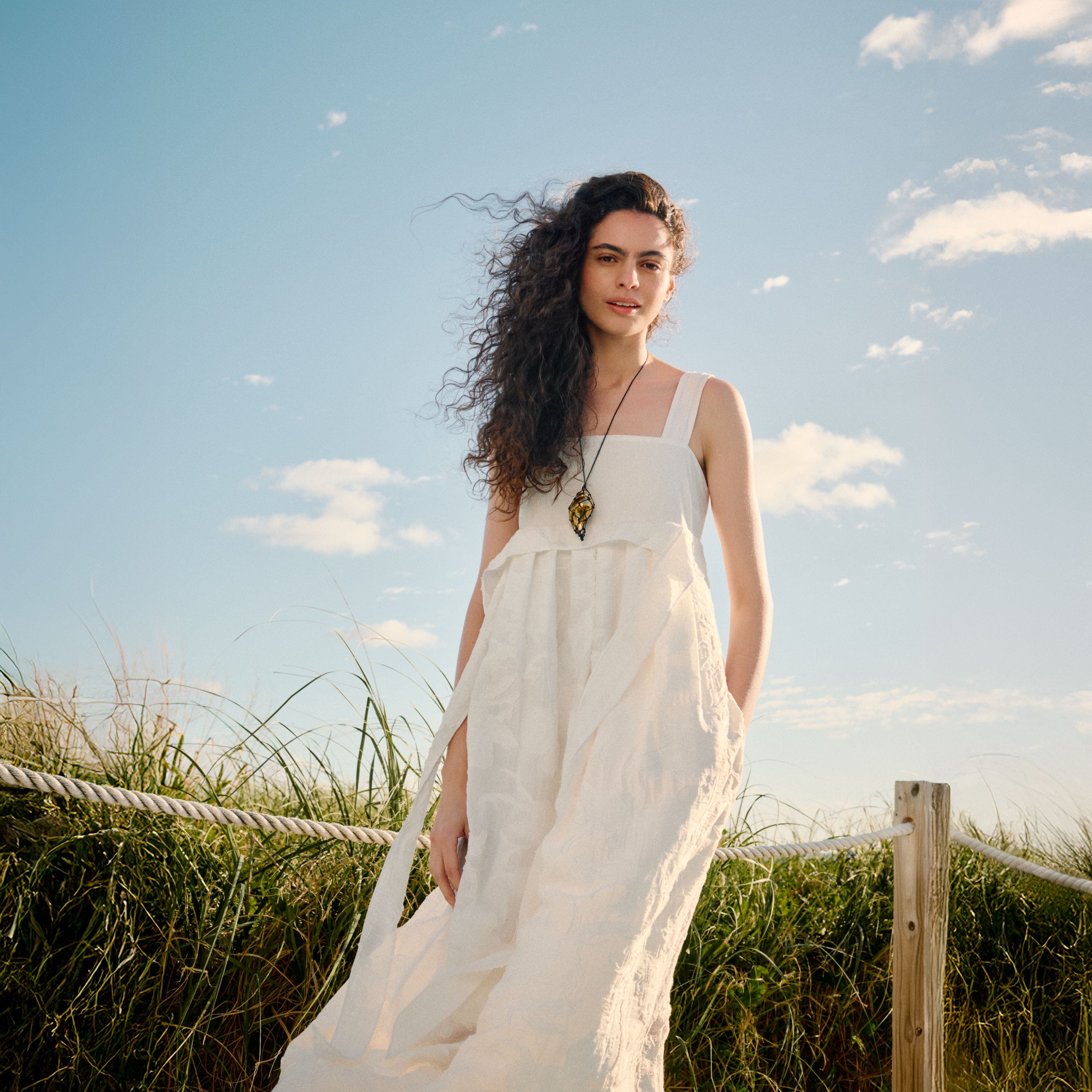 Woman wearing a white sundress and necklace.