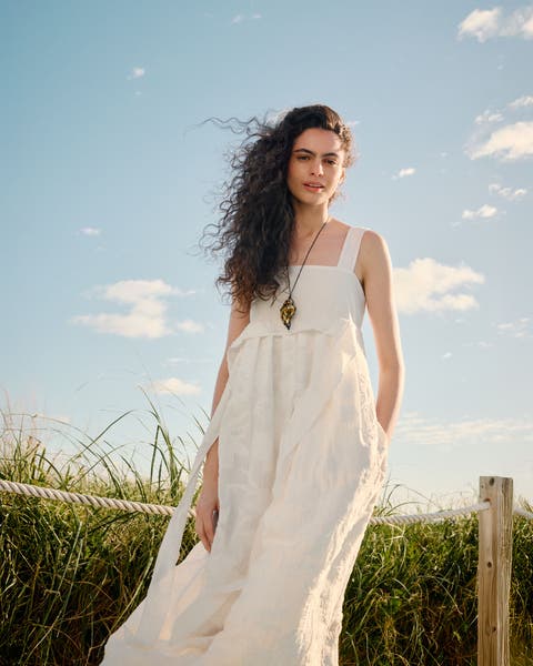 Woman wearing a white sundress and necklace.