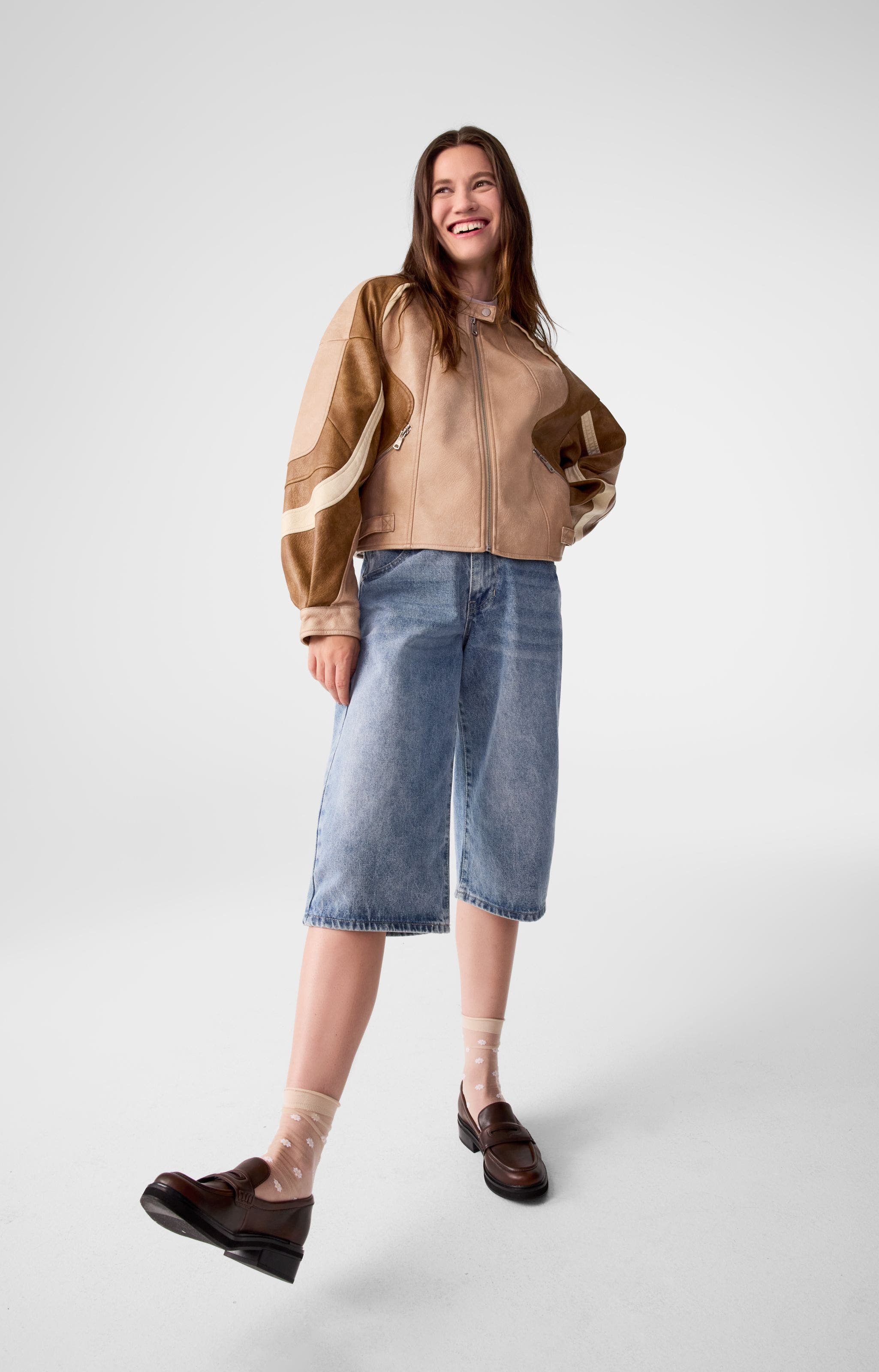 A woman wearing a patterned jacket and jeans. 