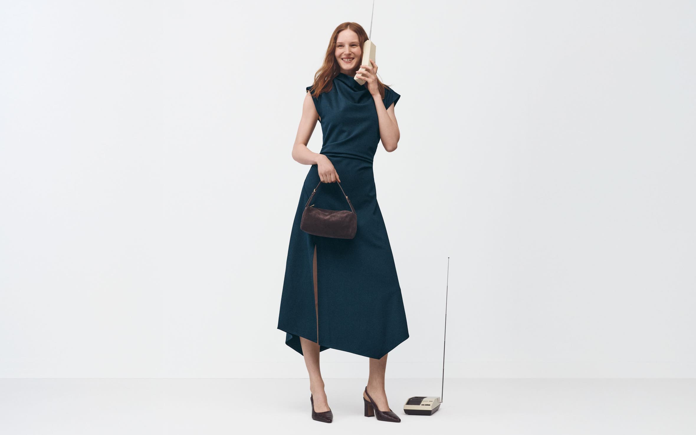 A woman wearing a dress and heels holding a handbag.