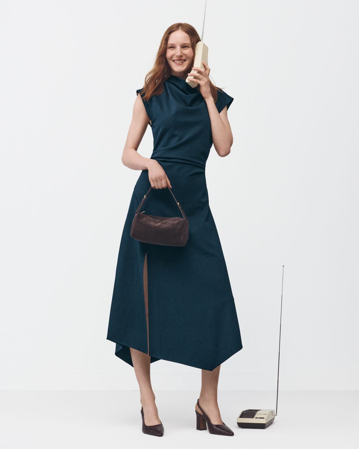 A woman wearing a dress and heels holding a handbag.
