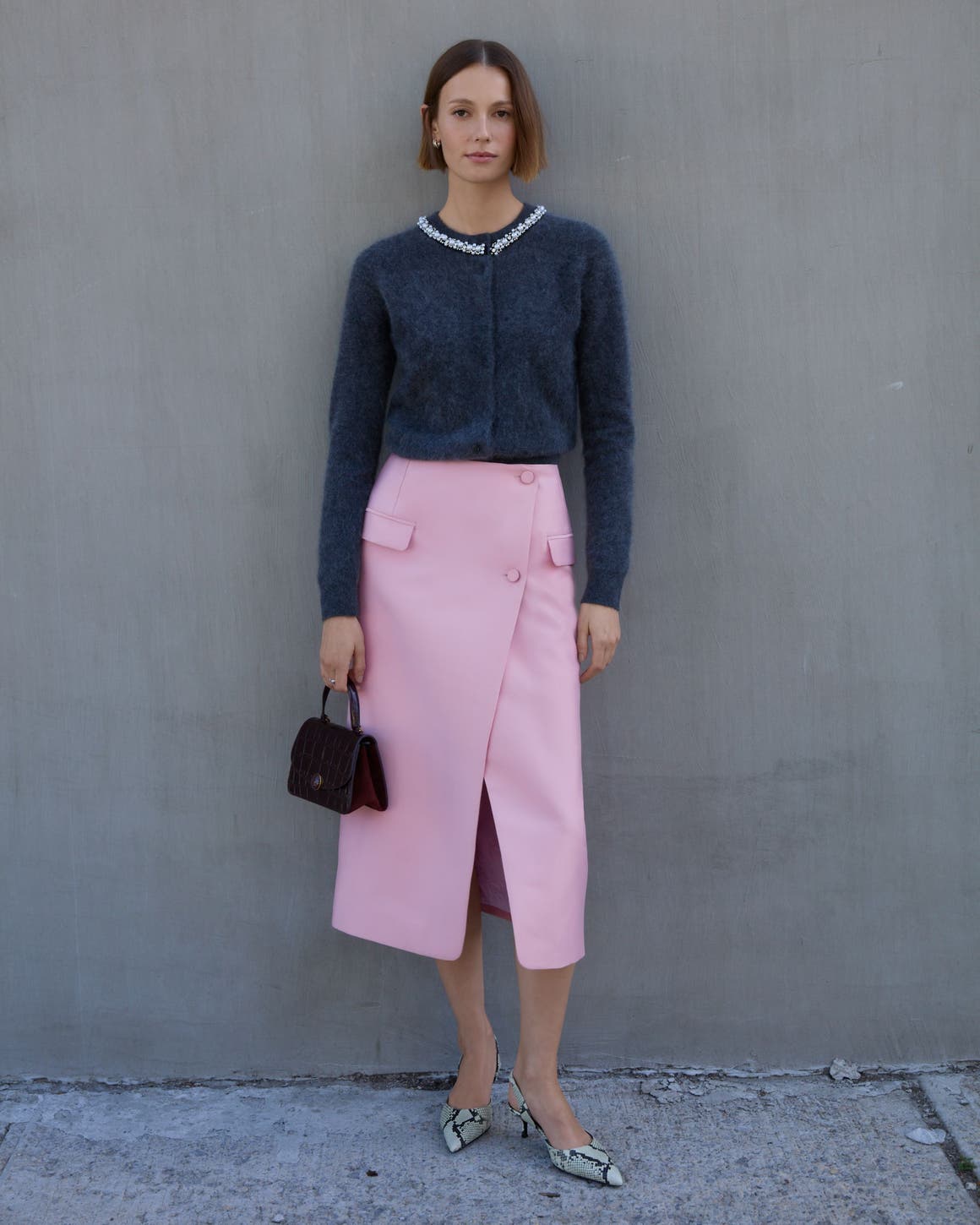 A woman wearing a cardigan and pink skirt.