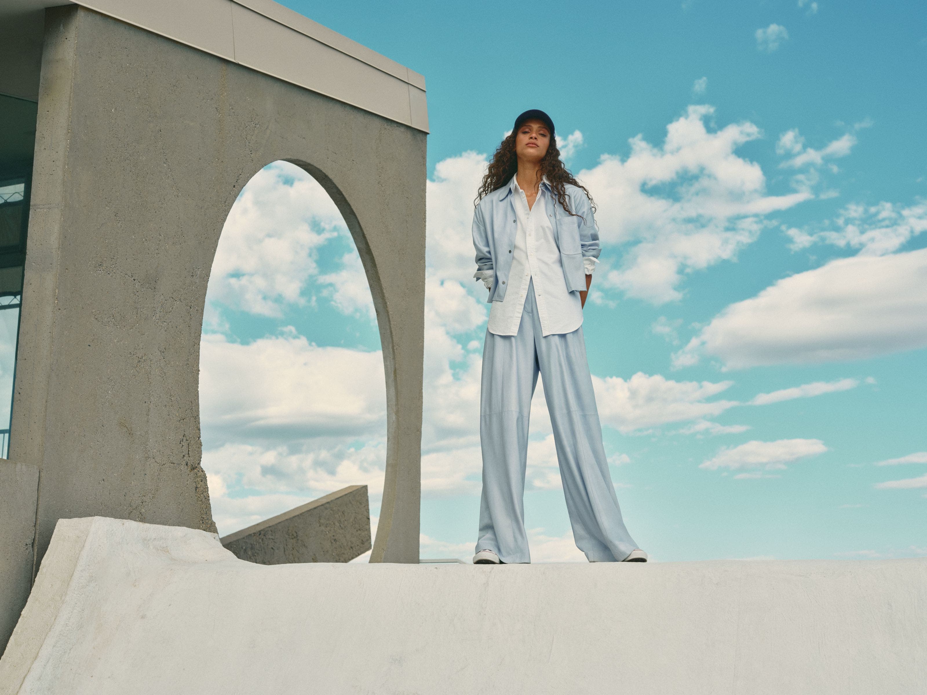Woman wearing a blue matching set with a white button-up shirt.