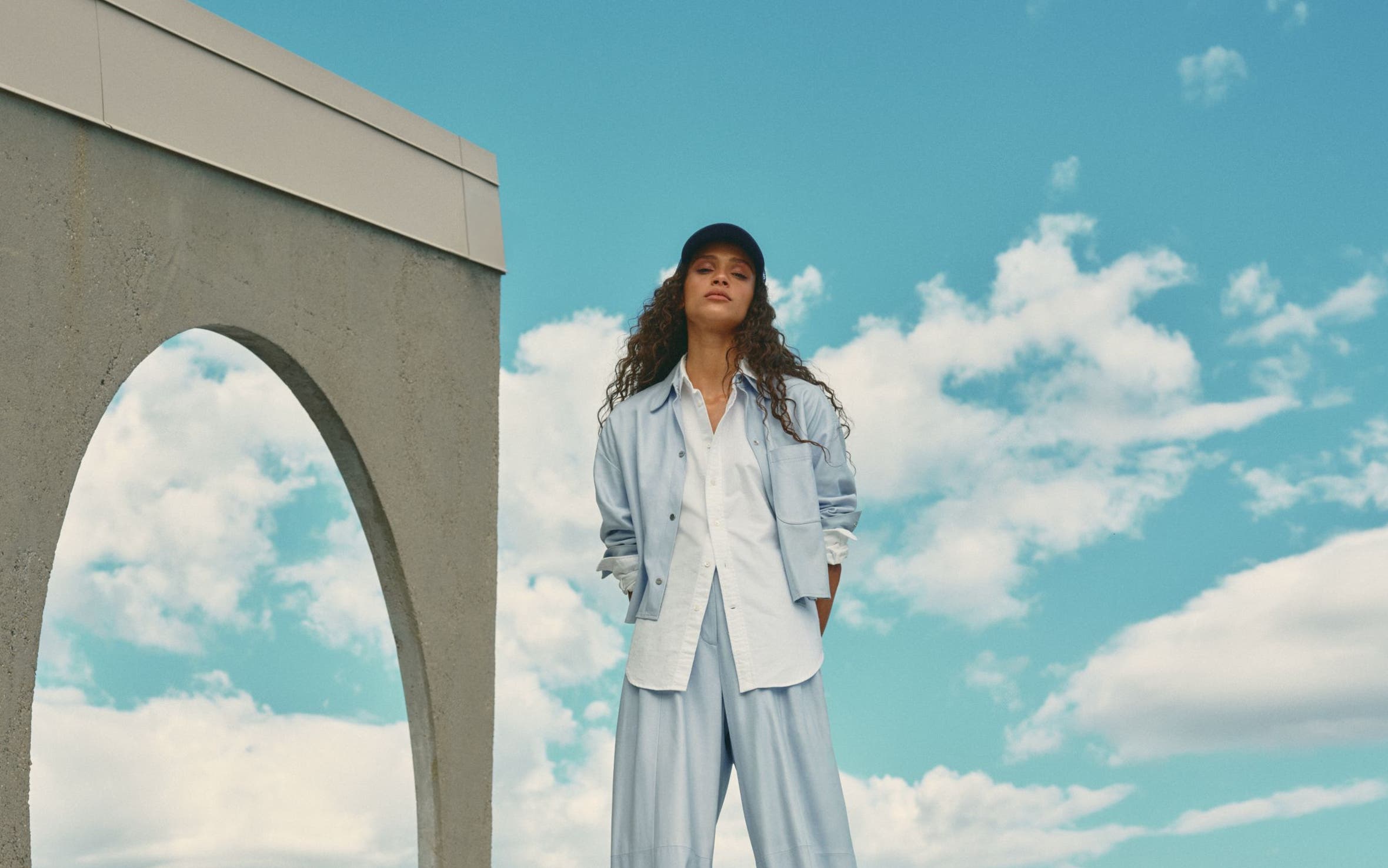 Woman wearing a blue matching set with a white button-up shirt.