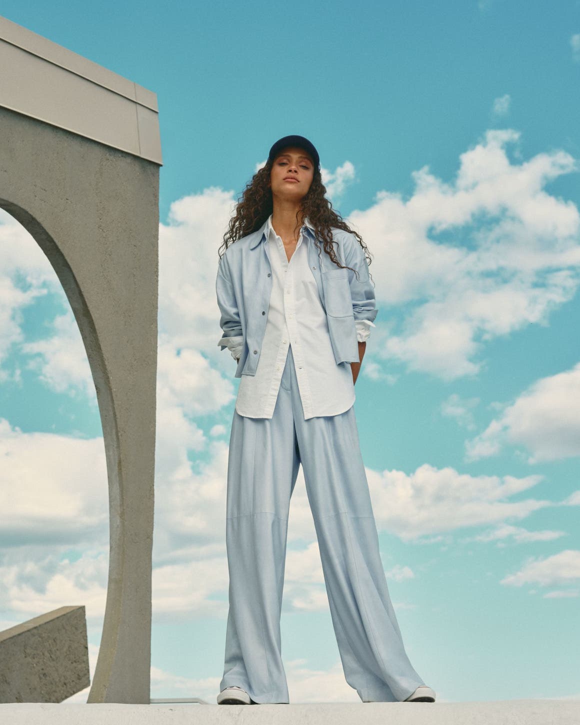 Woman wearing a blue matching set with a white button-up shirt.