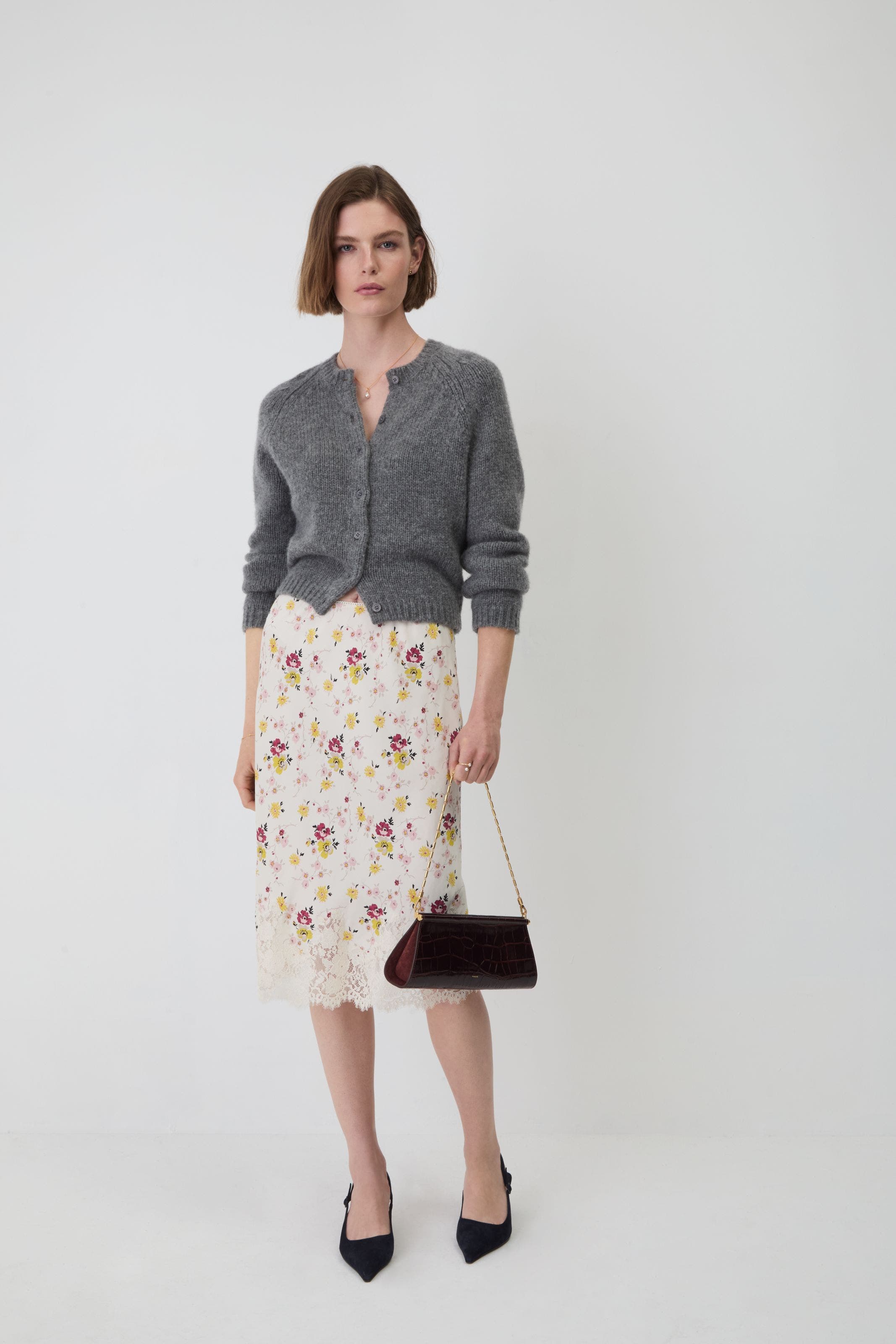 A woman wearing a grey cardigan and skirt.