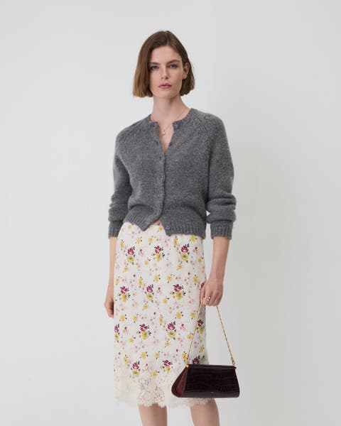 A woman wearing a grey cardigan and skirt.