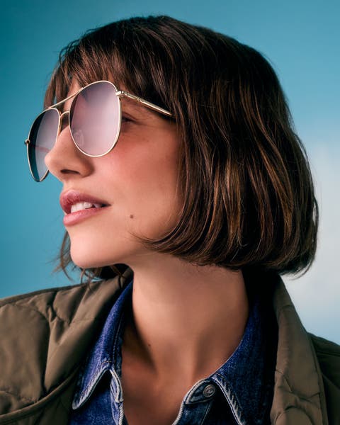 Woman wearing oversized gold aviator sunglasses.