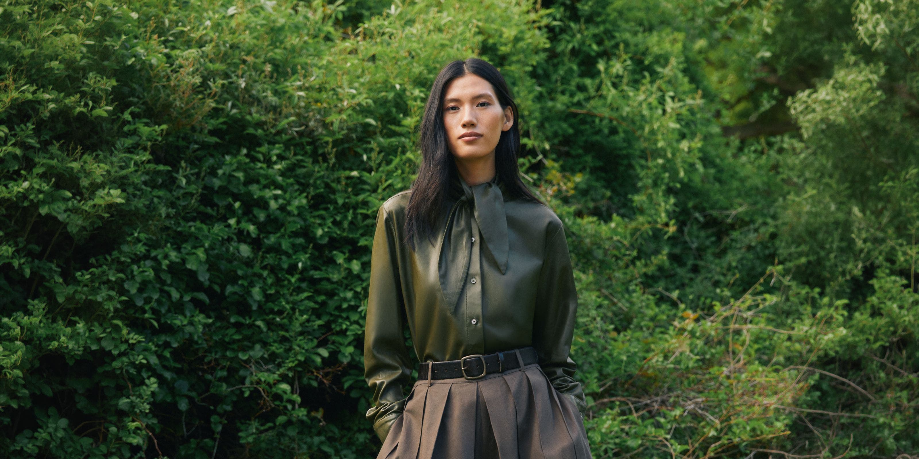 A woman wearing a button-up shirt and skirt.