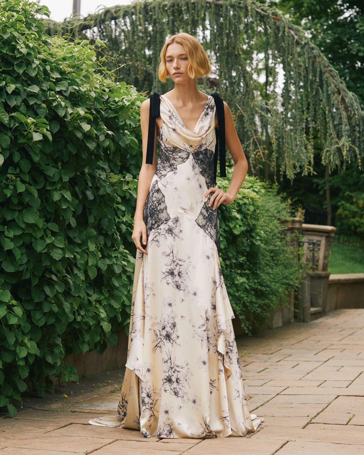 A woman wearing a white dress with black lace and florals.
