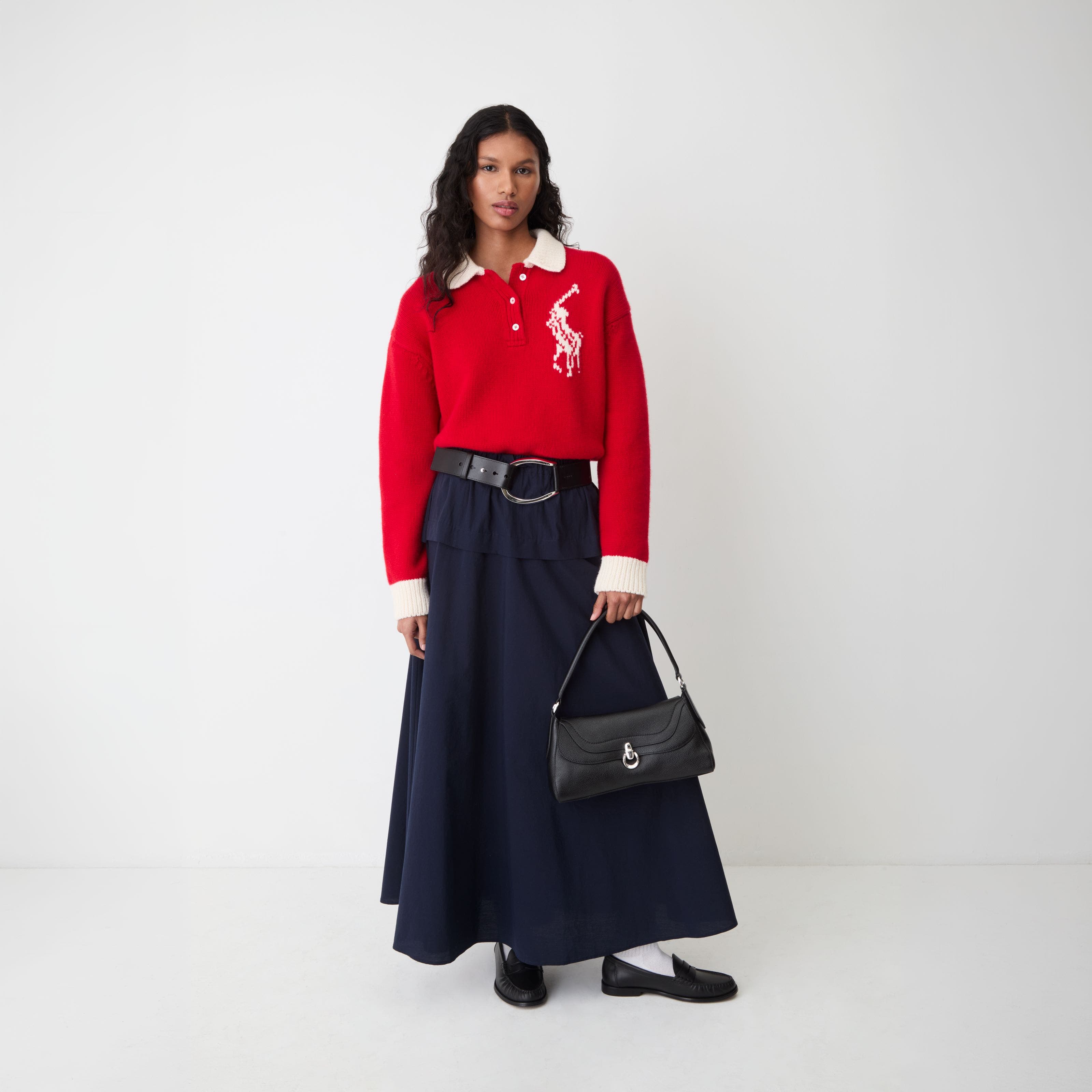 A woman wearing a red Polo Ralph Lauren sweater and a black maxi skirt.