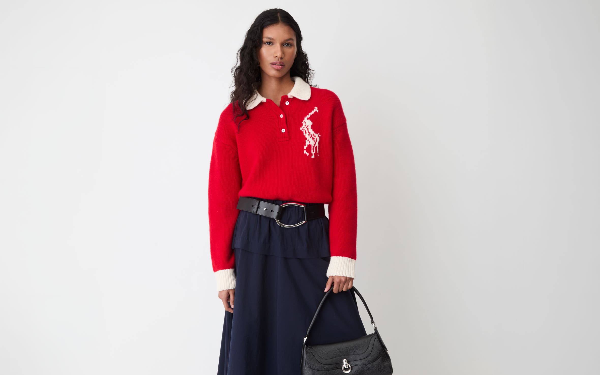 A woman wearing a red crewneck sweater and black maxi skirt.