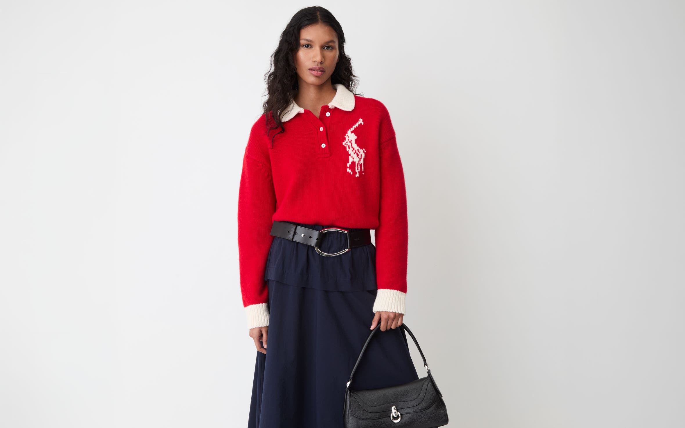 A woman wearing a red Polo Ralph Lauren sweater and a black maxi skirt.