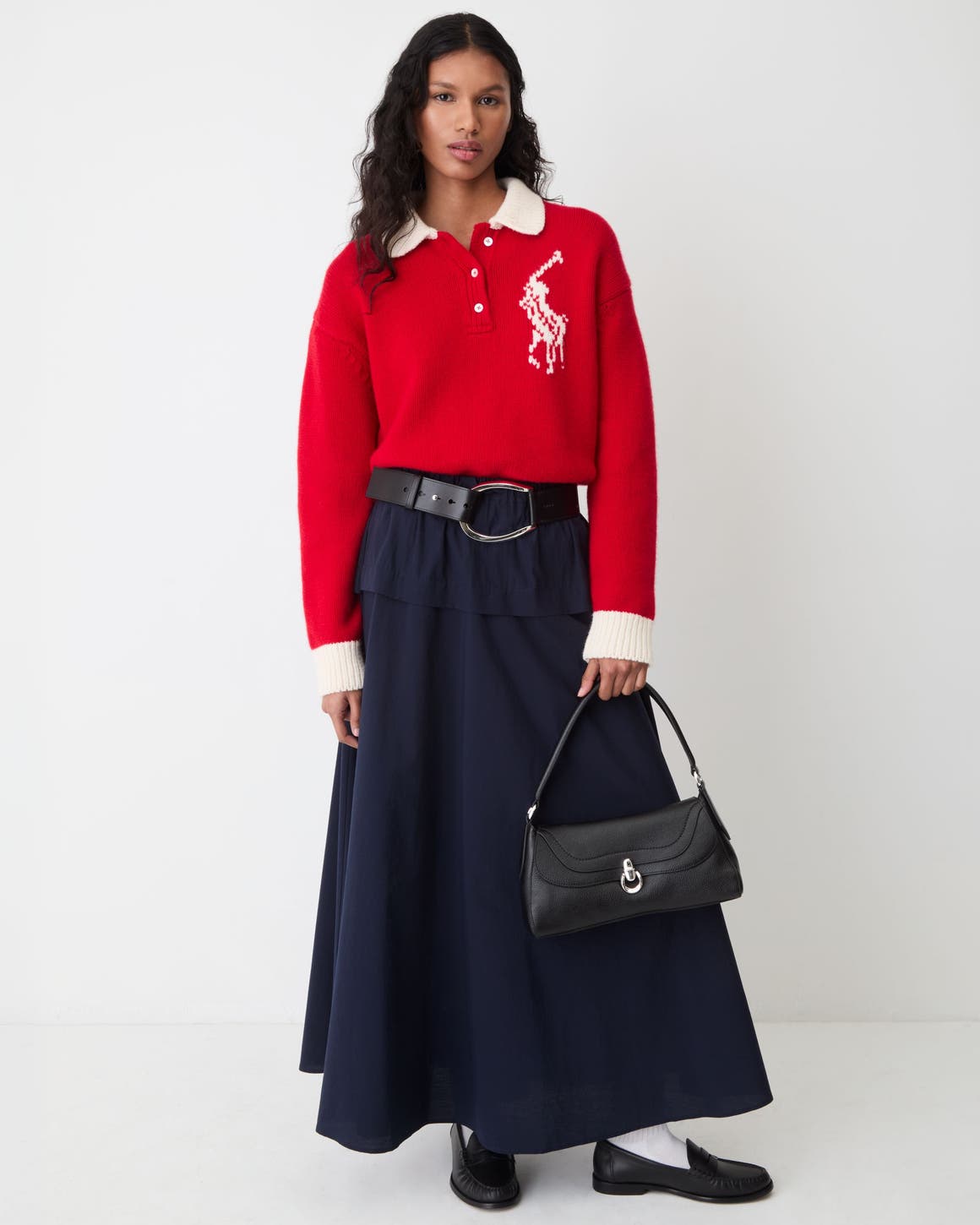 A woman wearing a red Polo Ralph Lauren sweater and a black maxi skirt.