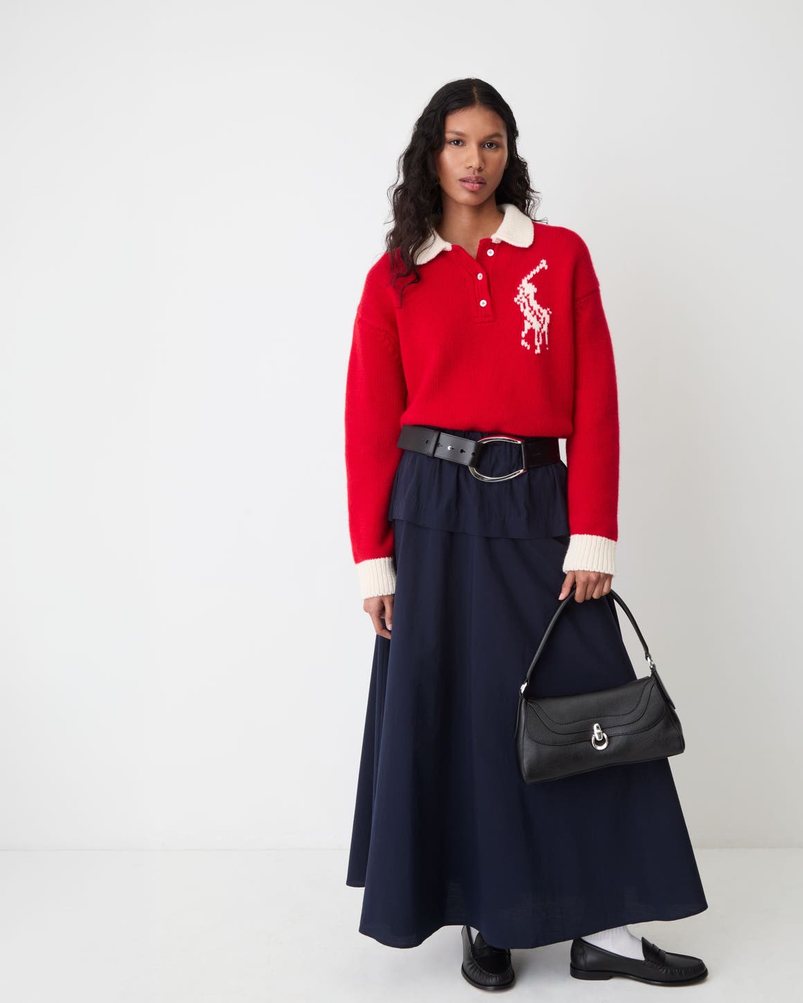 A woman wearing a red Polo Ralph Lauren sweater and a black maxi skirt.