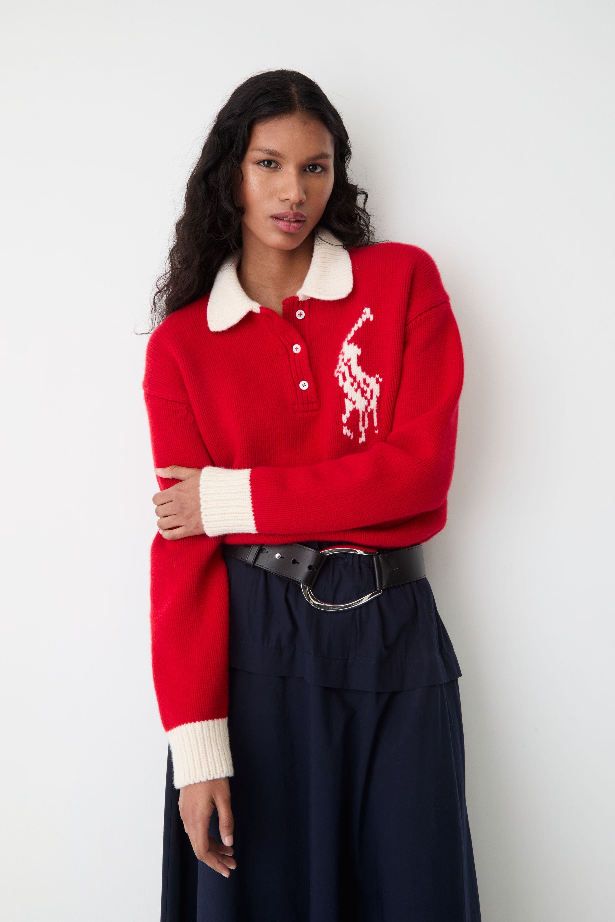 A woman in a red wool rugby polo sweater with logo detail.