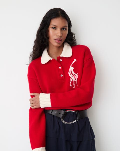 A woman in a red wool rugby polo sweater with logo detail.