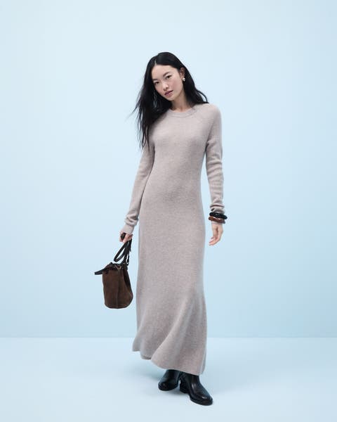 Woman wearing a cashmere maxi dress, bangles, boots and a handbag.