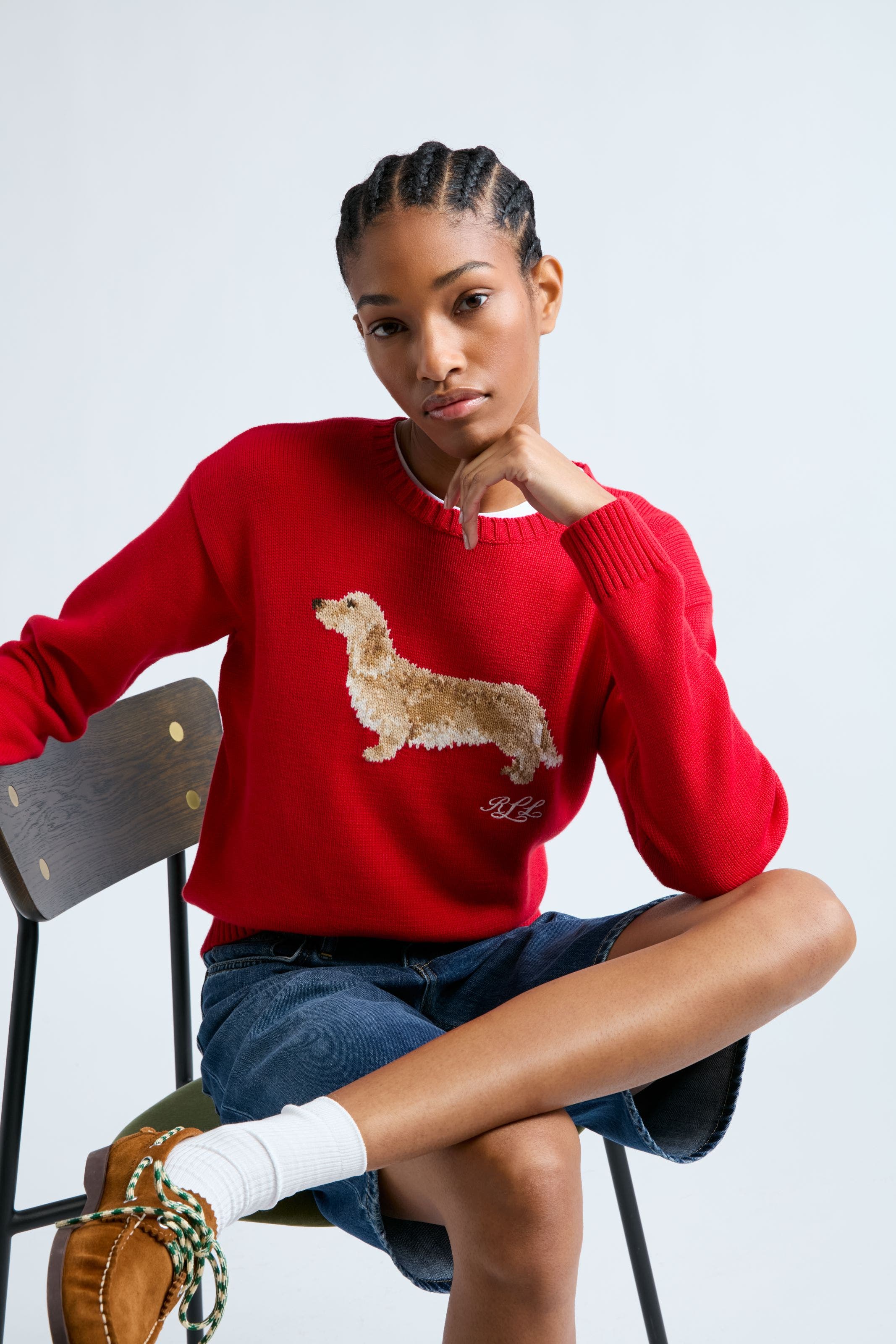 A woman wearing a red pullover sweater with a dog image. 