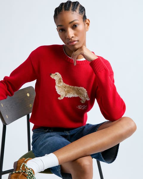 Woman wearing a sweater, denim shorts, socks and boat shoes.