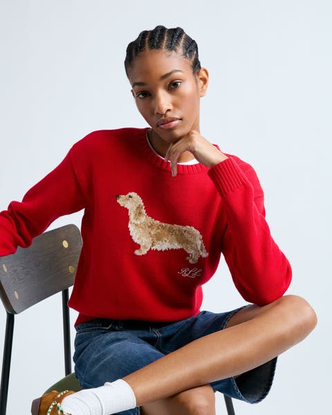 A woman wearing a red pullover sweater with a dog image.