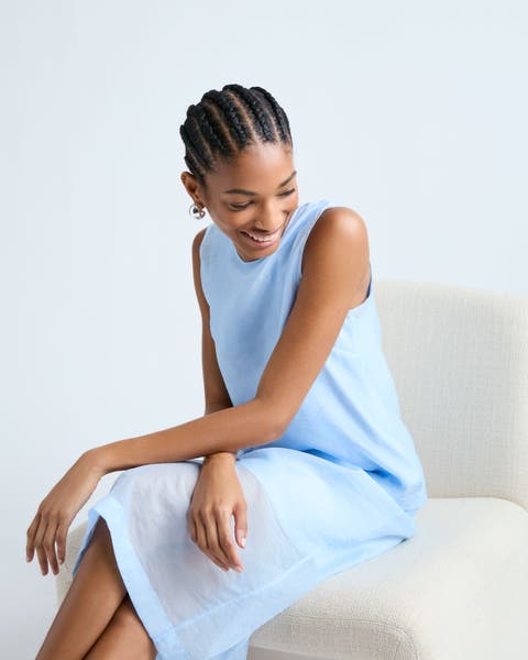 Woman wearing light blue sleeveless top and skirt.