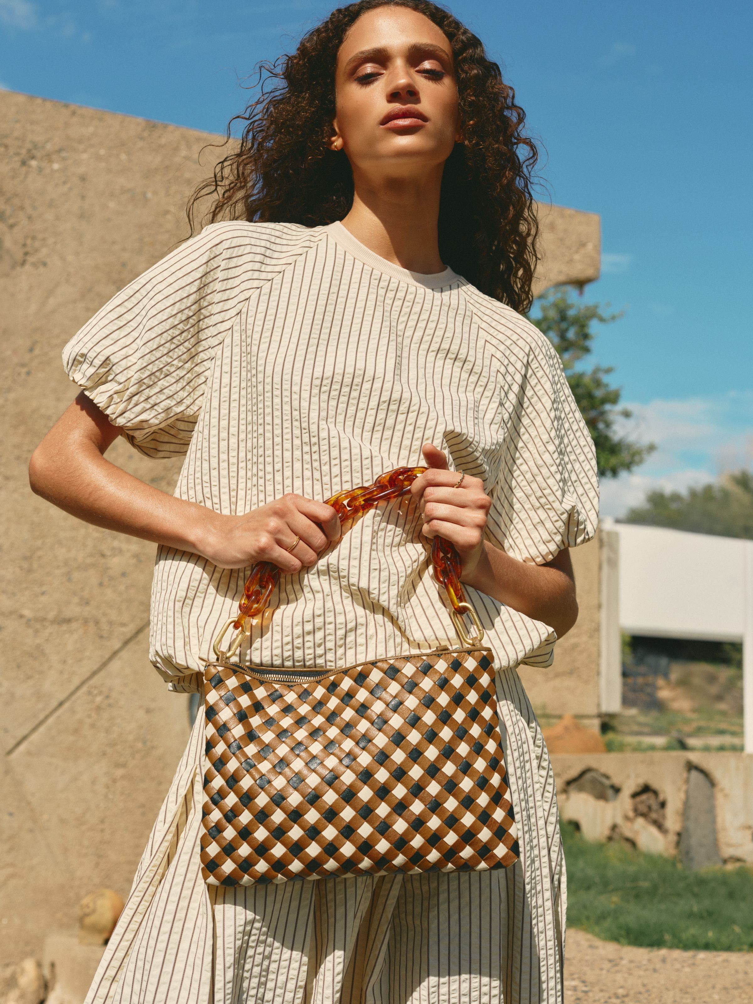 A woman holding a woven handbag. 