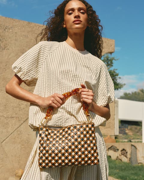 A woman holding a woven handbag.