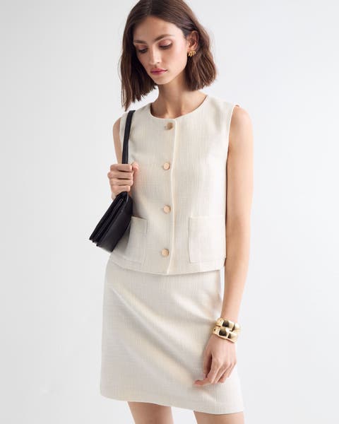 women wearing white tweed matching set sleeveless button up top and knee length skirt.