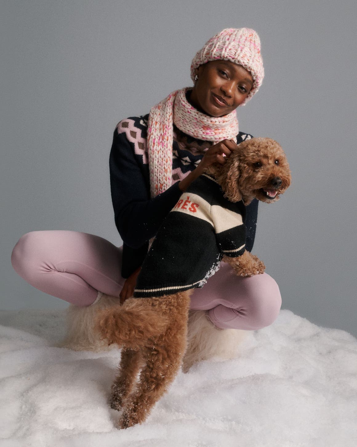 A woman wearing outerwear with a dog in a sweater.