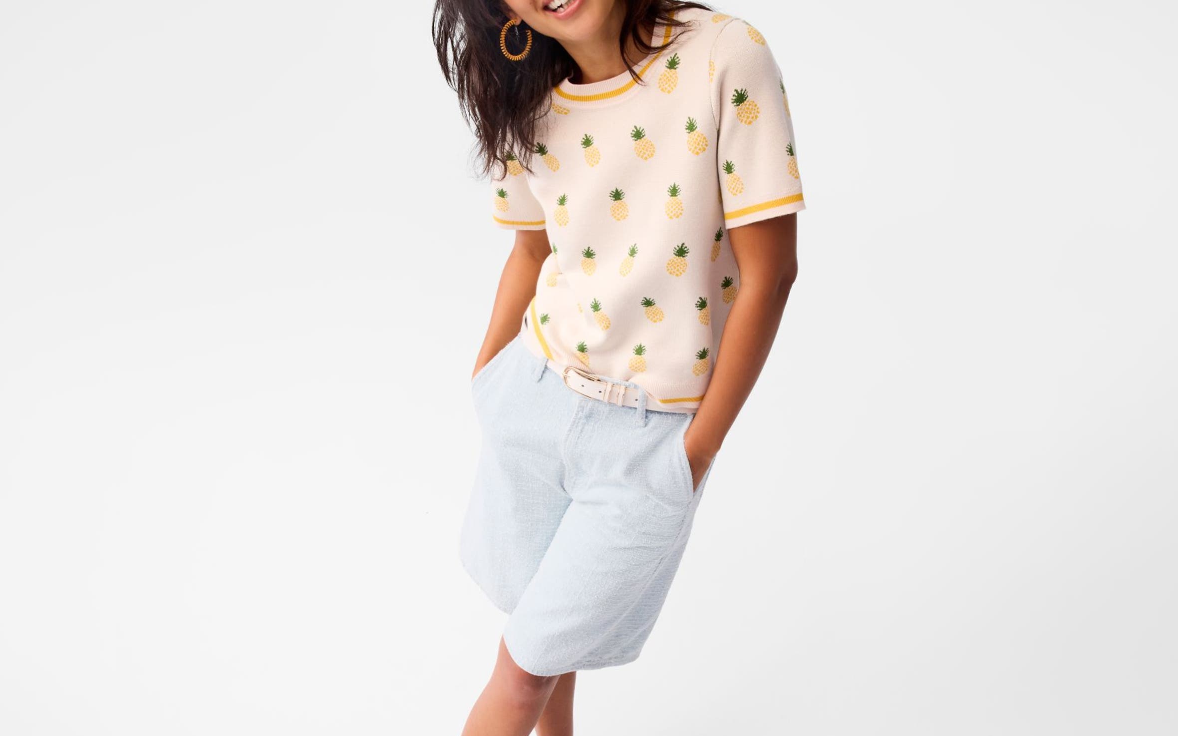 A woman wearing a printed top, shorts and loafers.