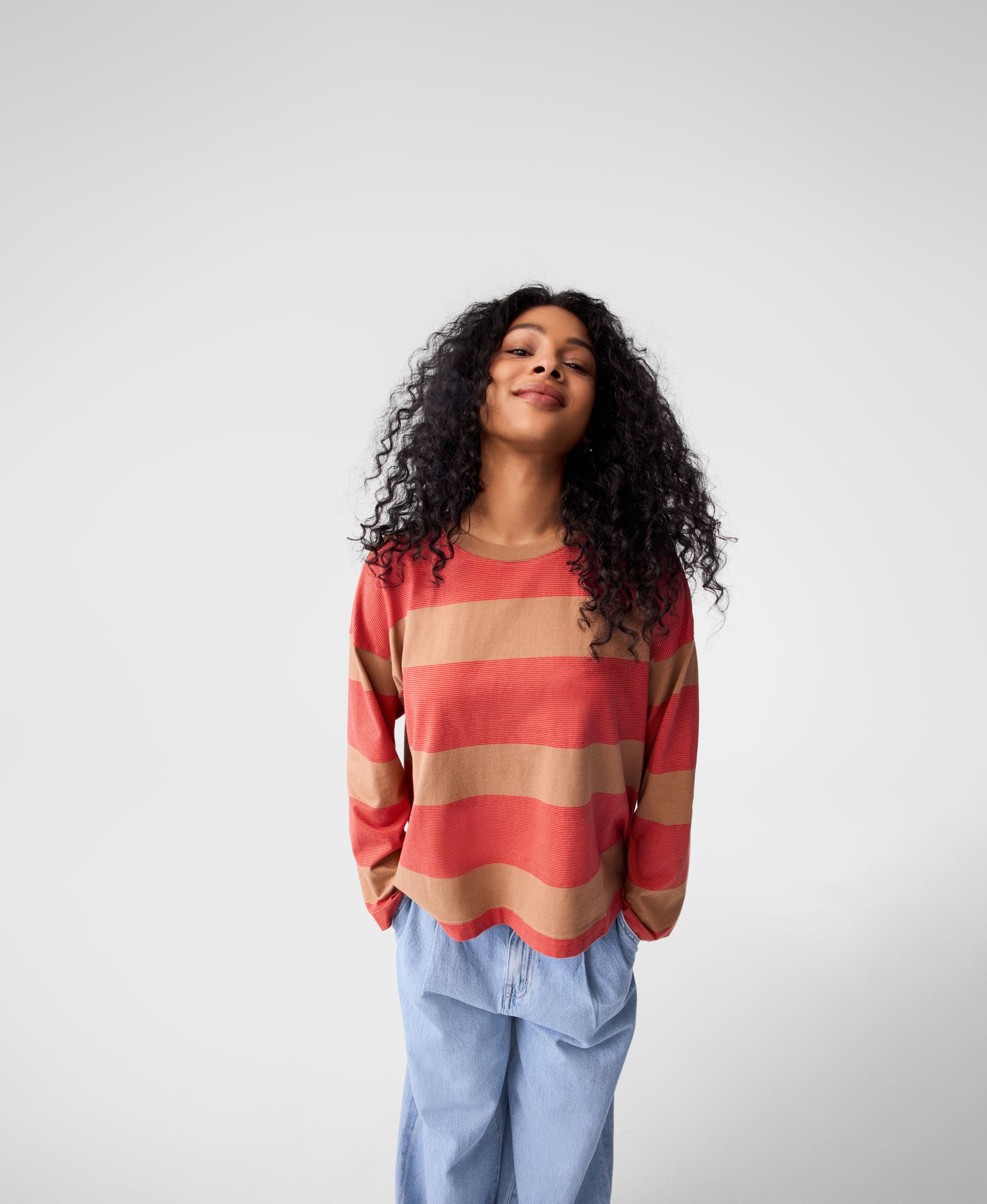 A woman wearing a striped long-sleeve top with jeans. 