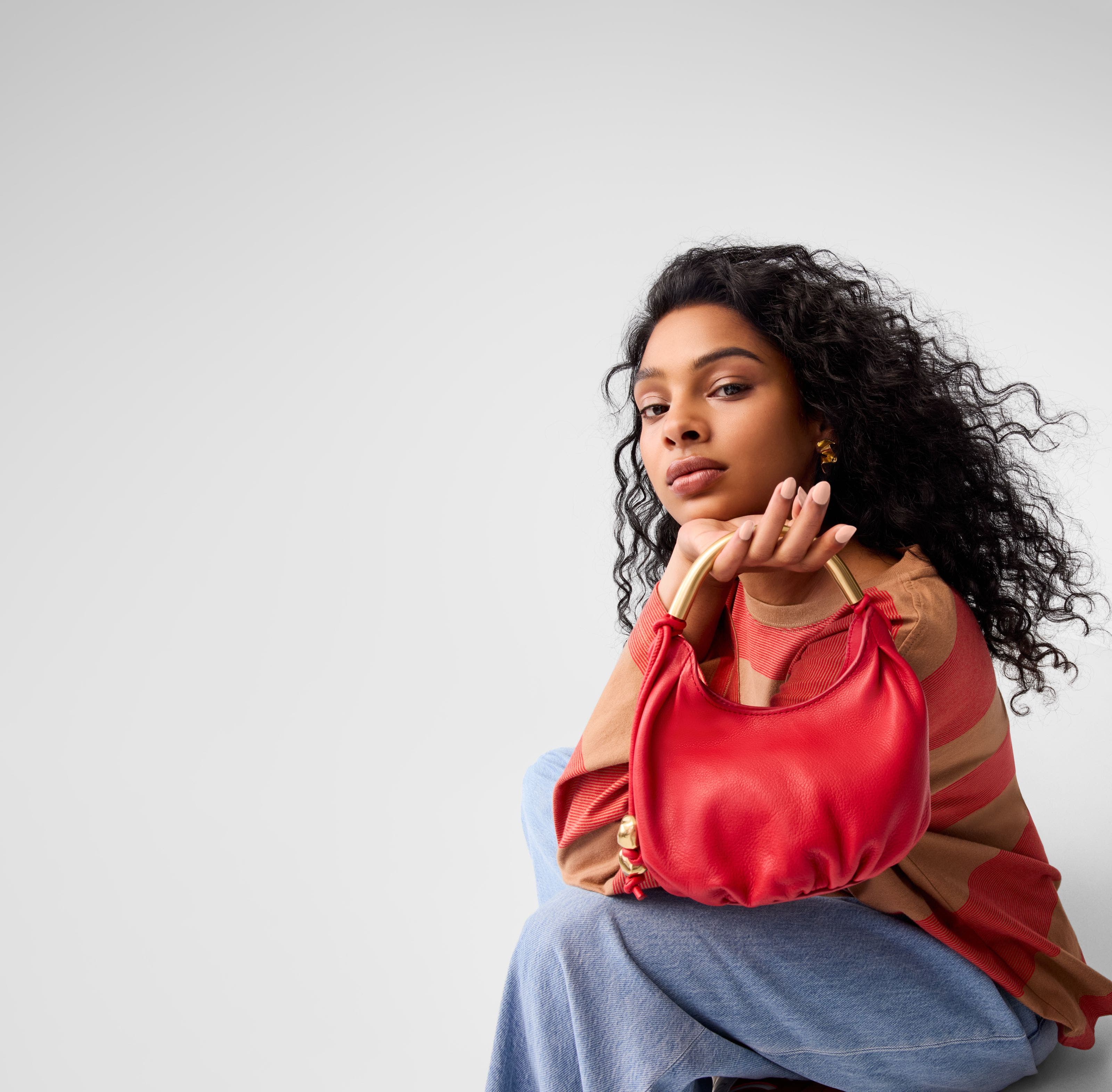 A woman holding a red handbag.