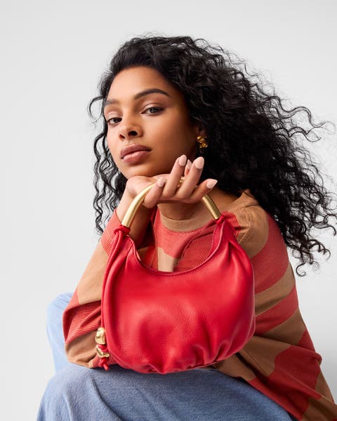 A woman holding a red handbag.