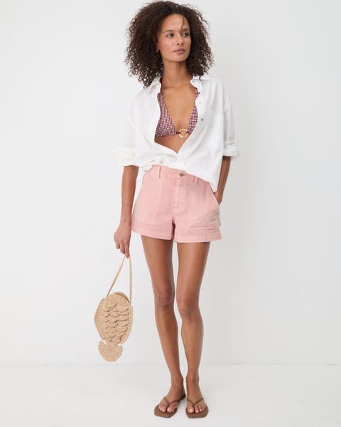 Woman wearing white top, pink shorts and sandals.