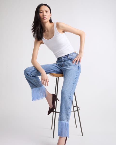 A woman wearing embellished fringe hemmed denim.