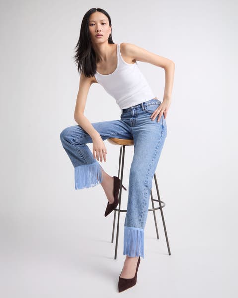 A woman wearing embellished fringe hemmed denim.
