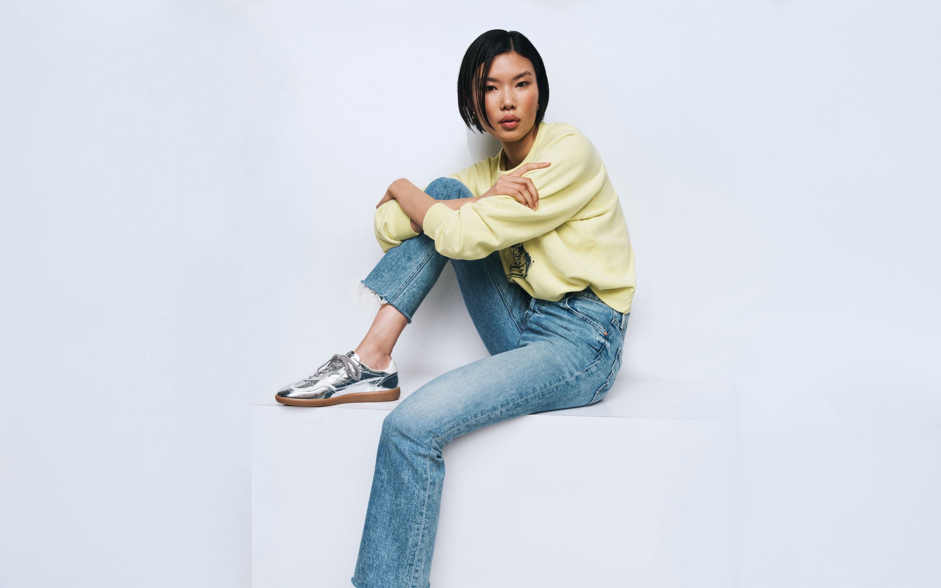 Woman wearing a sweatshirt, denim jeans and sneakers.