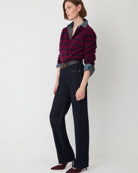 A woman in a red and navy plaid sweater, dark denim jeans.