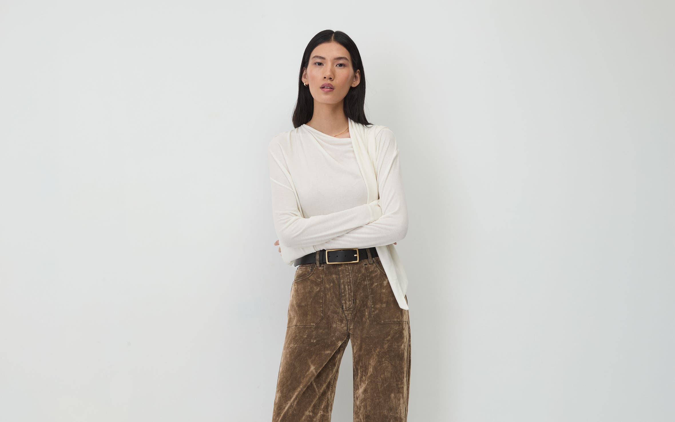 A woman wearing a white top and brown trousers.